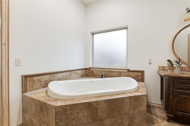 bathroom featuring tile patterned floors, vanity, and tiled bath