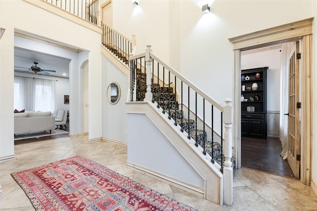 stairway with ceiling fan, a towering ceiling, and tile patterned floors