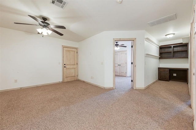 interior space featuring built in desk, light colored carpet, and ceiling fan