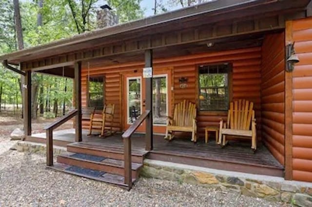 entrance to property with faux log siding and a chimney