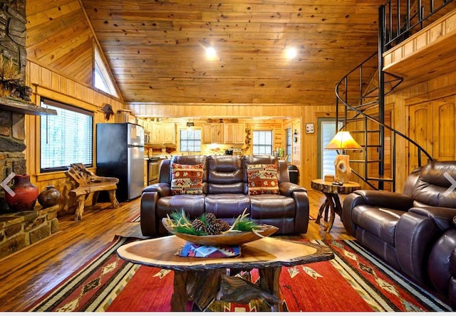 living room with wood walls, wood finished floors, high vaulted ceiling, wooden ceiling, and stairs