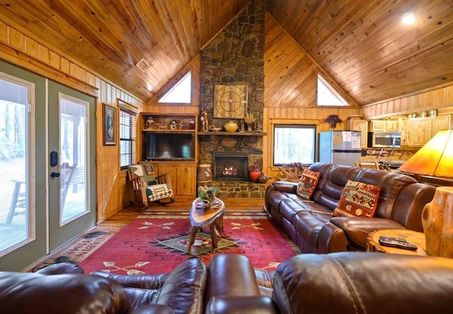 living area featuring a fireplace, wooden walls, wood finished floors, high vaulted ceiling, and wooden ceiling