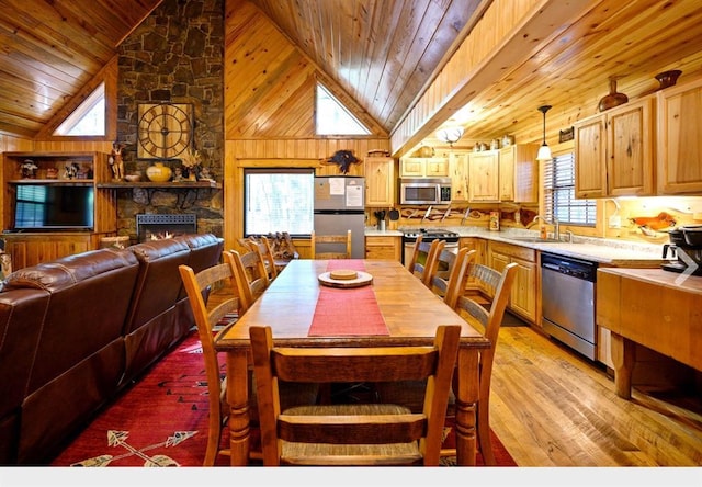 dining space with wooden walls, light wood finished floors, wood ceiling, and a healthy amount of sunlight