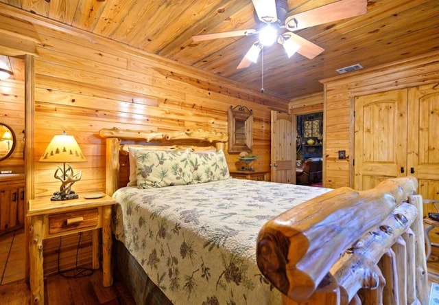 bedroom featuring visible vents, ceiling fan, wooden walls, wood finished floors, and wooden ceiling