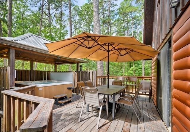 deck with outdoor dining area and a hot tub