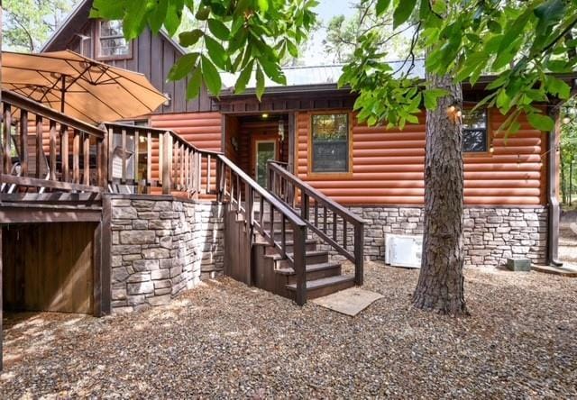 exterior space with metal roof, stone siding, and faux log siding