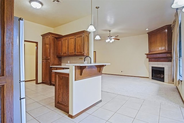 kitchen featuring pendant lighting, a breakfast bar area, ceiling fan, kitchen peninsula, and light carpet