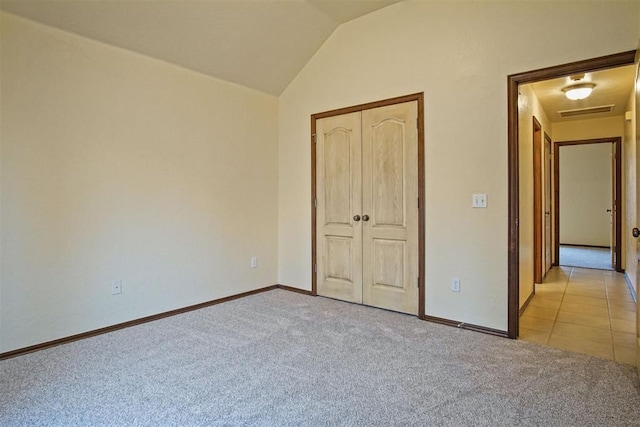 unfurnished bedroom featuring light carpet, vaulted ceiling, and a closet