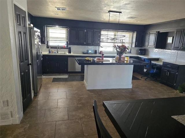 kitchen with tasteful backsplash, stainless steel refrigerator with ice dispenser, a healthy amount of sunlight, and pendant lighting