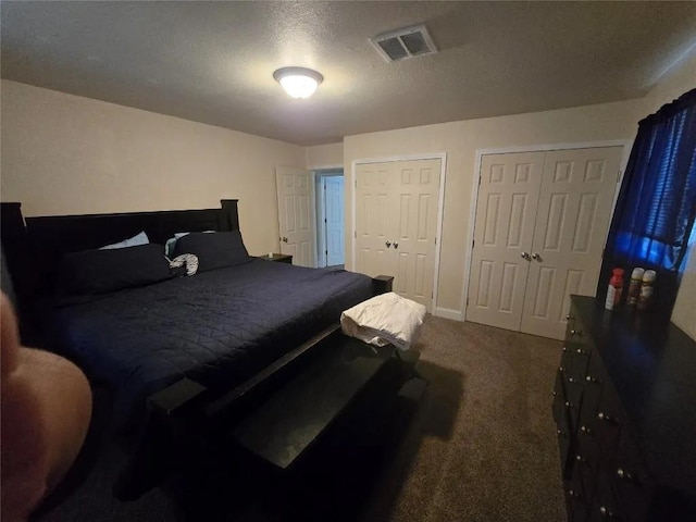 carpeted bedroom featuring two closets and a textured ceiling