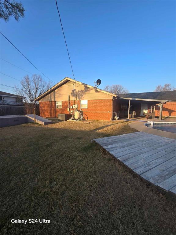 back of house featuring a swimming pool side deck and a yard