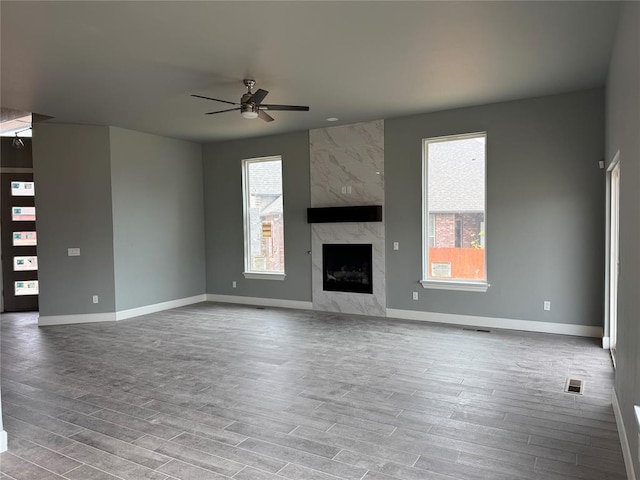 unfurnished living room featuring hardwood / wood-style flooring, ceiling fan, and a high end fireplace