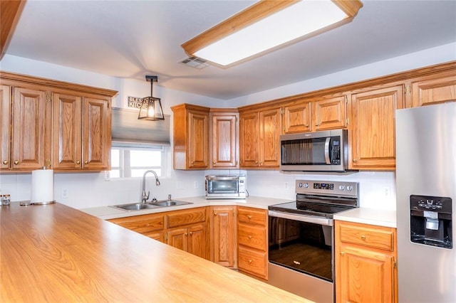 kitchen featuring sink, wooden counters, decorative light fixtures, stainless steel appliances, and decorative backsplash