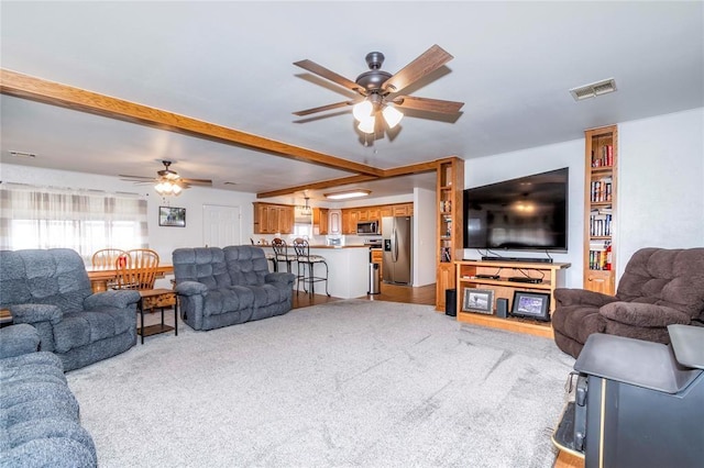 living room with ceiling fan, light colored carpet, and beam ceiling