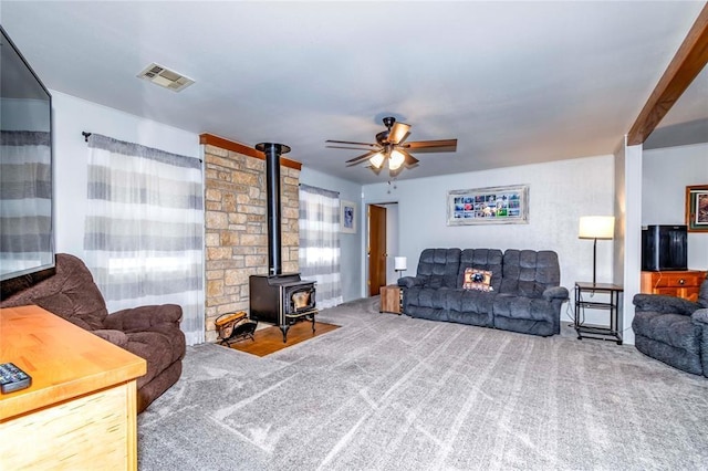 living room with carpet floors, ceiling fan, and a wood stove