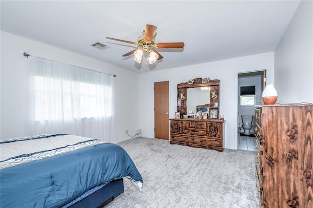 carpeted bedroom with ensuite bath and ceiling fan