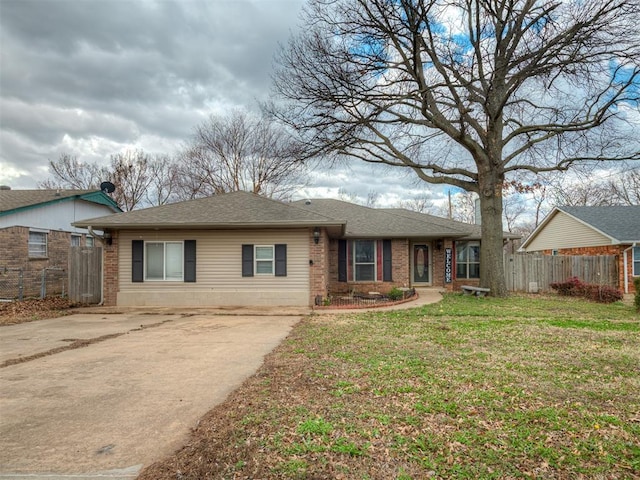 ranch-style home featuring roof with shingles, brick siding, a front lawn, and fence