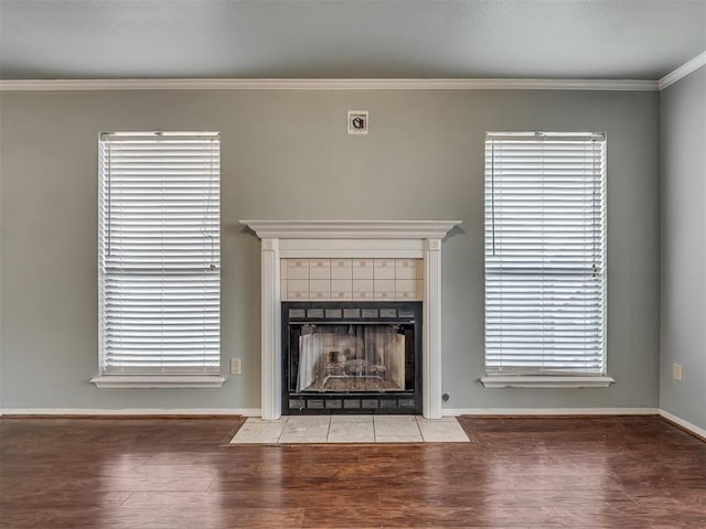 unfurnished living room featuring baseboards, a fireplace, wood finished floors, and crown molding