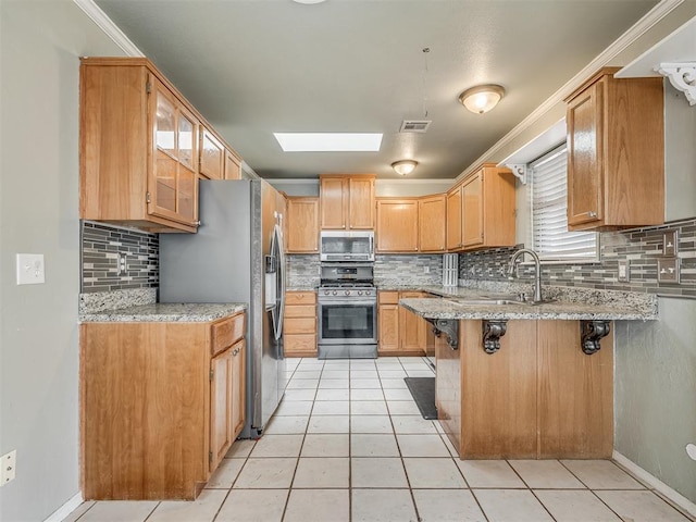 kitchen featuring a skylight, visible vents, appliances with stainless steel finishes, a peninsula, and a sink