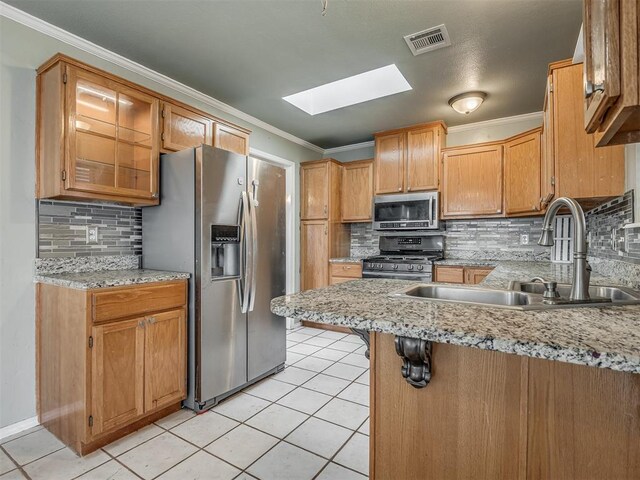 kitchen with a skylight, a sink, visible vents, appliances with stainless steel finishes, and crown molding