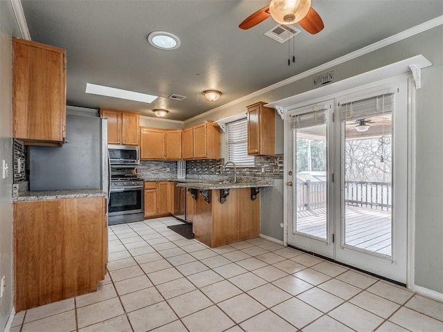 kitchen with a skylight, visible vents, stainless steel appliances, and crown molding