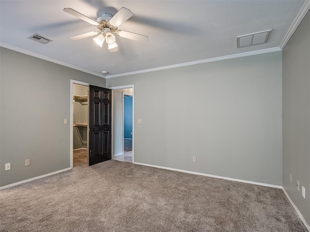 unfurnished room featuring baseboards, visible vents, crown molding, and carpet flooring