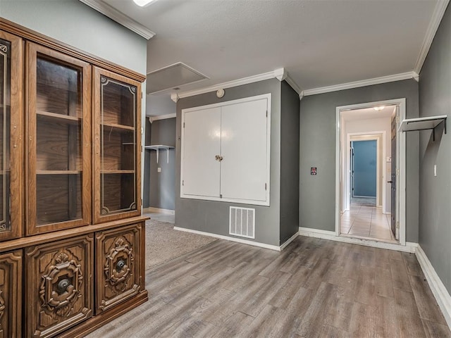 interior space with attic access, baseboards, visible vents, wood finished floors, and crown molding