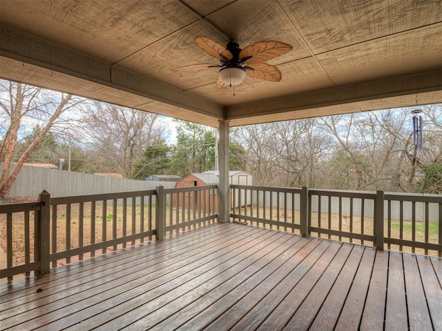 wooden deck featuring a storage shed, an outbuilding, a fenced backyard, and a ceiling fan