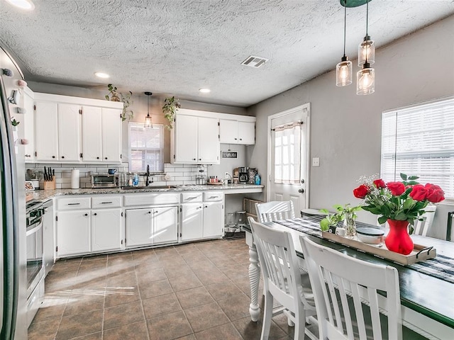 kitchen with pendant lighting, light stone counters, and white cabinetry