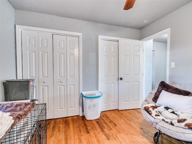 bedroom with ceiling fan, light hardwood / wood-style floors, and two closets