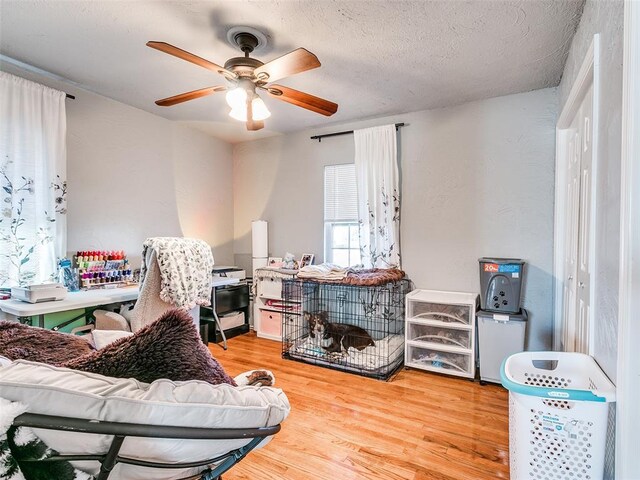 interior space with ceiling fan, wood-type flooring, and a textured ceiling