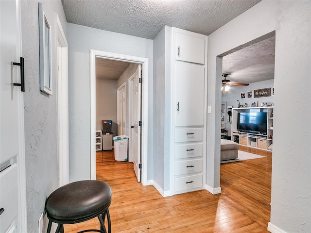 corridor with light hardwood / wood-style flooring and a textured ceiling