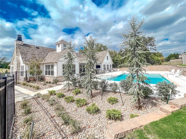 back of property with a fenced in pool and a patio area