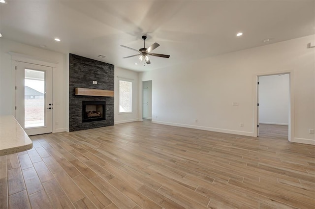 unfurnished living room featuring light wood-type flooring, ceiling fan, and a fireplace