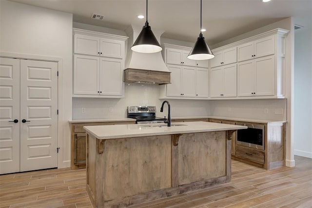 kitchen with a center island with sink, white cabinetry, and pendant lighting