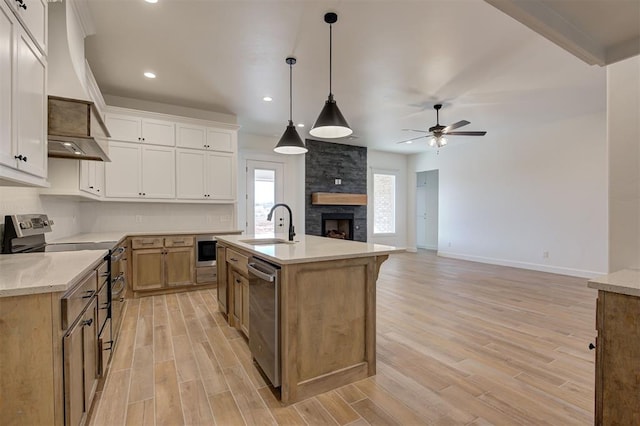 kitchen featuring white cabinetry, a kitchen island with sink, light hardwood / wood-style floors, appliances with stainless steel finishes, and pendant lighting