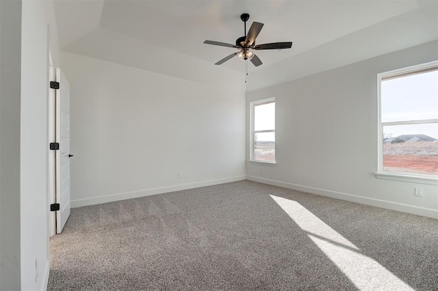 carpeted empty room featuring a tray ceiling and ceiling fan