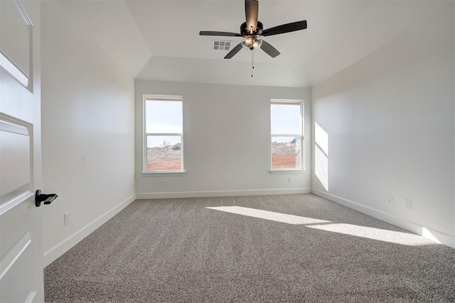 empty room featuring a tray ceiling, light carpet, and ceiling fan