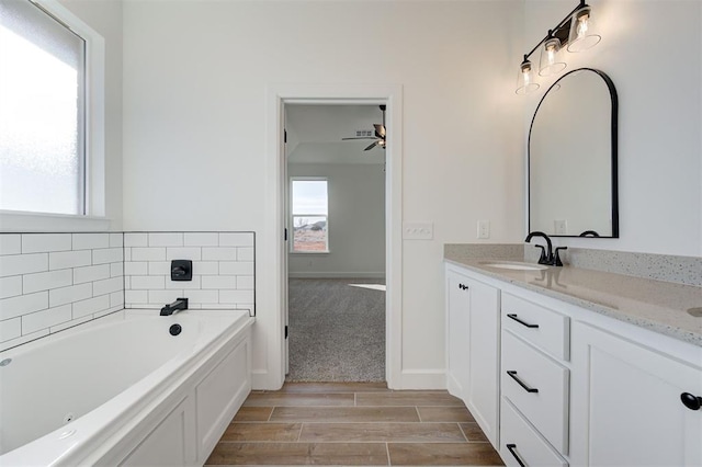 bathroom with a washtub, a wealth of natural light, ceiling fan, and vanity