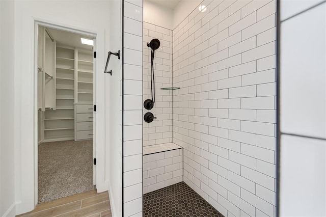 bathroom with tiled shower and hardwood / wood-style flooring