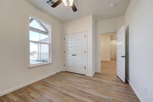 unfurnished bedroom featuring light wood-type flooring, a closet, and ceiling fan