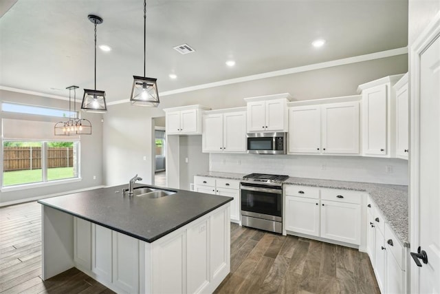 kitchen featuring sink, stainless steel appliances, white cabinets, and a center island with sink