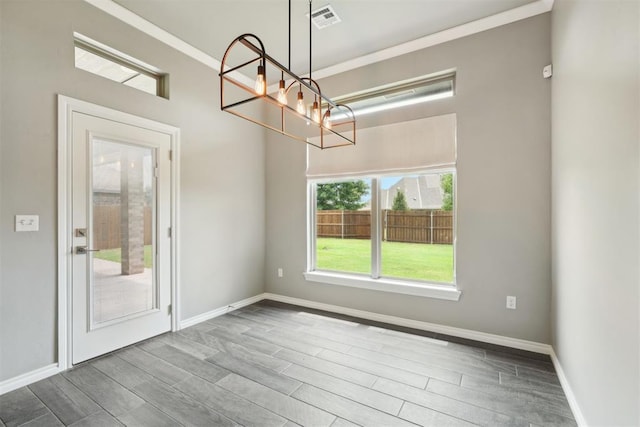 unfurnished dining area featuring crown molding, hardwood / wood-style floors, and a notable chandelier