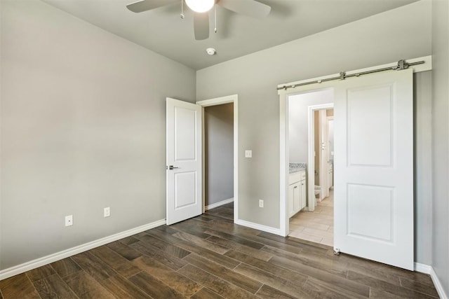 unfurnished bedroom with ceiling fan and a barn door