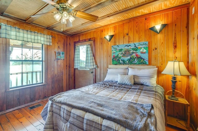 bedroom with wood ceiling, wooden walls, wood-type flooring, and beam ceiling