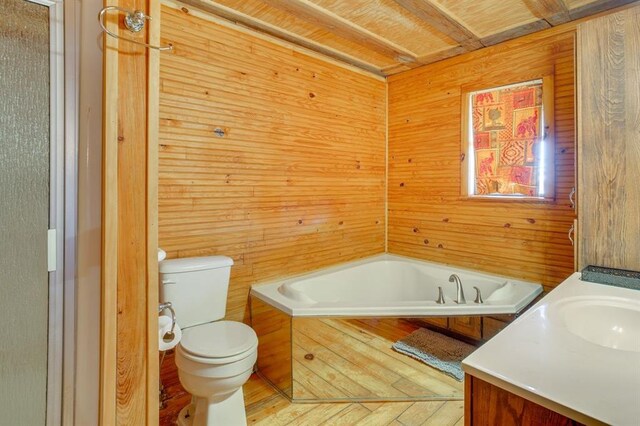 bathroom featuring vanity, toilet, a bathing tub, and wood walls