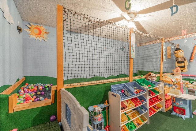 recreation room with a textured ceiling, ceiling fan, and carpet flooring