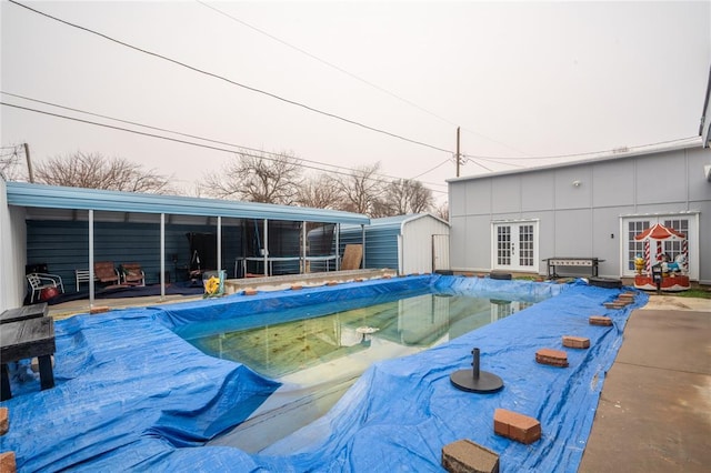 view of swimming pool featuring french doors, a patio area, and a shed