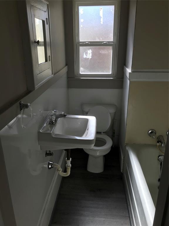 bathroom featuring toilet, a bathing tub, sink, and hardwood / wood-style floors