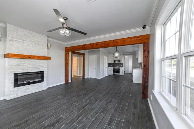 unfurnished living room with a fireplace, sink, ornamental molding, ceiling fan, and dark wood-type flooring